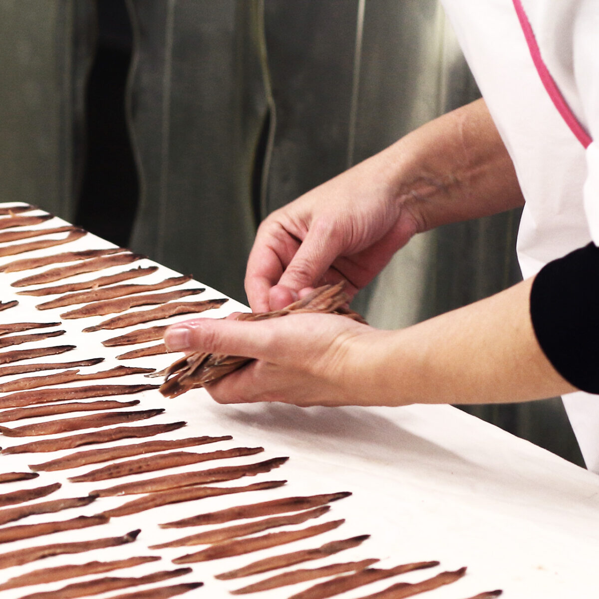 Image of a person stretching anchovies along a table.